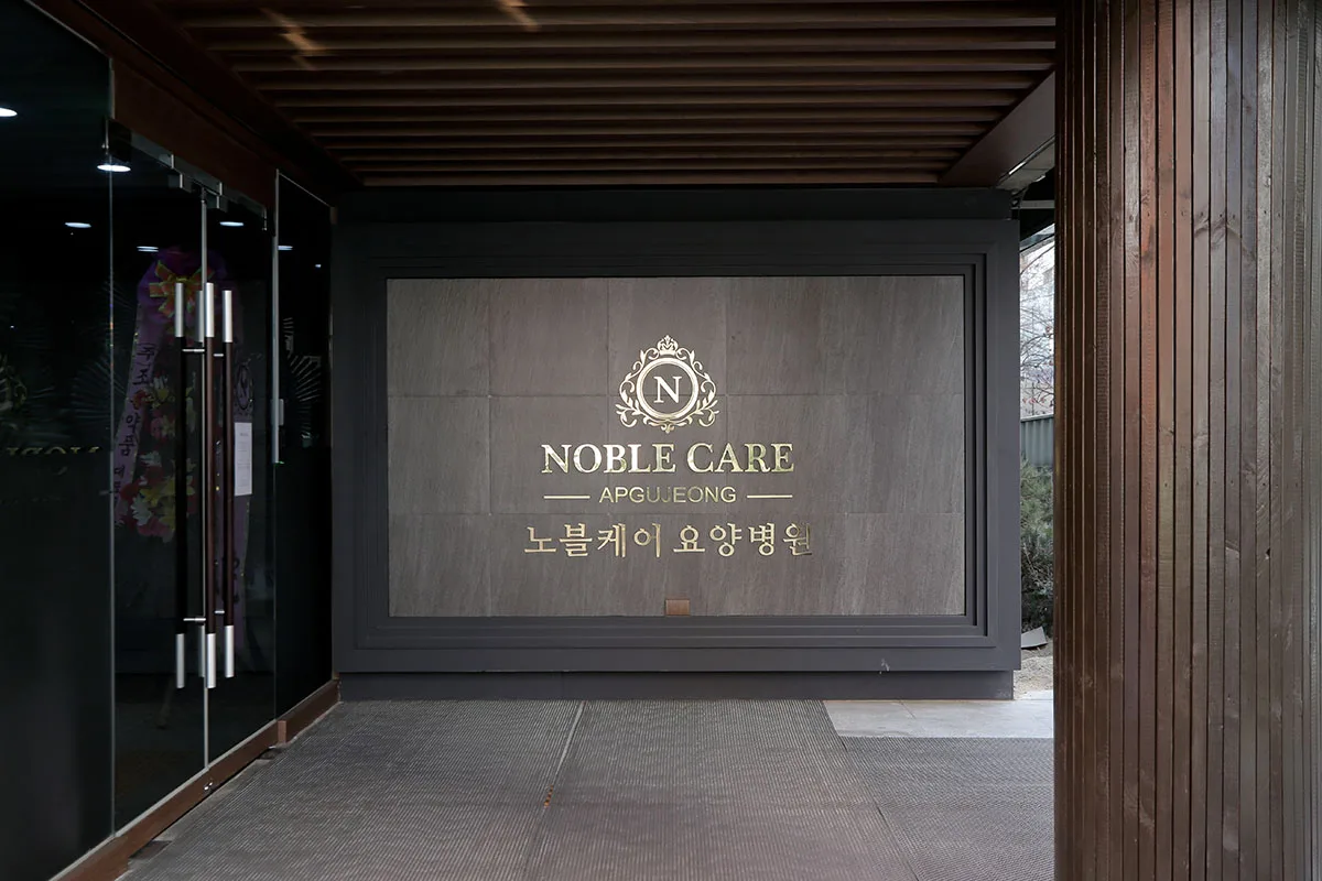3관 현관 안쪽. 금색 노블케어 엠블럼이 새겨진 어두운 벽면