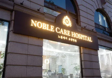 건물 벽에 붙은 NOBLE CARE HOSPITAL 금색 간판과 노블케어 요양병원 한글 표기