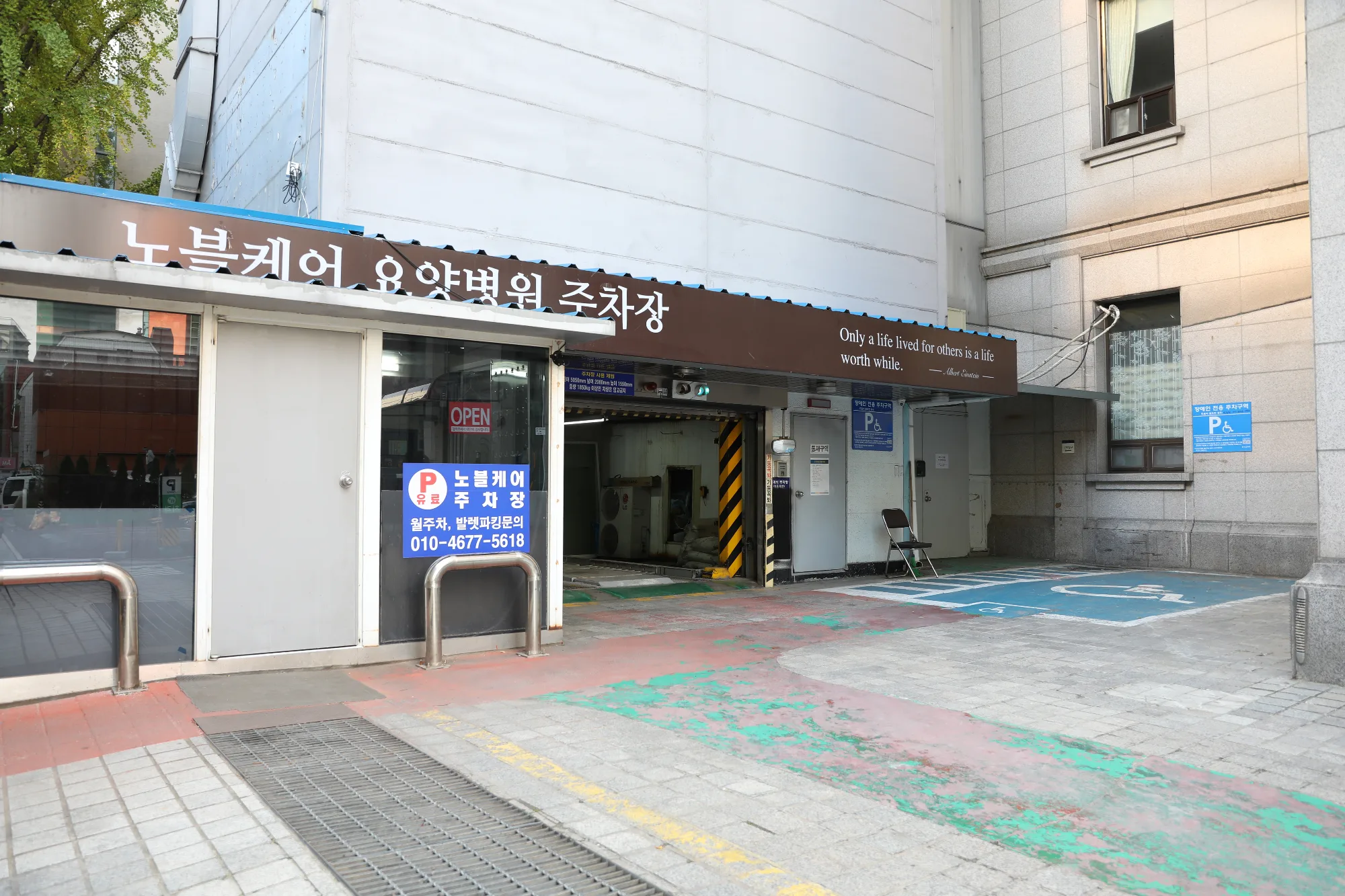 노블케어 요양병원 주차장 입구. 갈색 차양에 주차장 표시와 장애인 주차구역이 있다