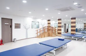 물리치료실 입구 쪽. 나무 계단 훈련 기구와 치료 베드