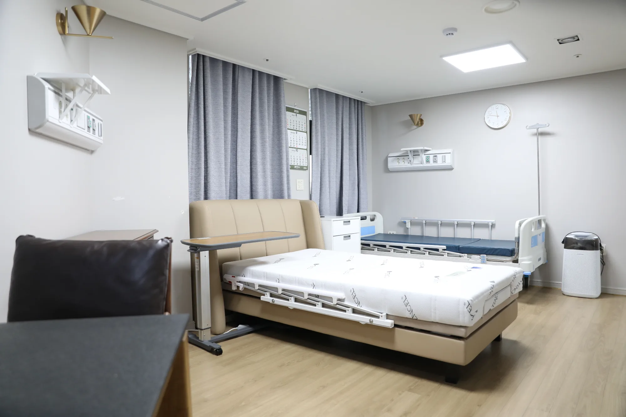 VIP 병실. 전동 침대와 이동식 식탁, 공기청정기와 보호자 소파